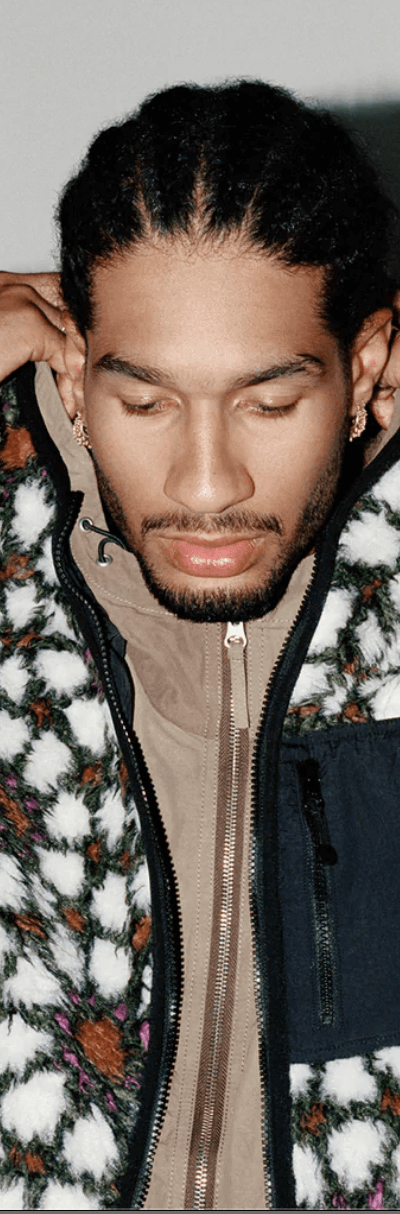 A man wearing a white and brown Stussy fleece with a brown jacket underneath