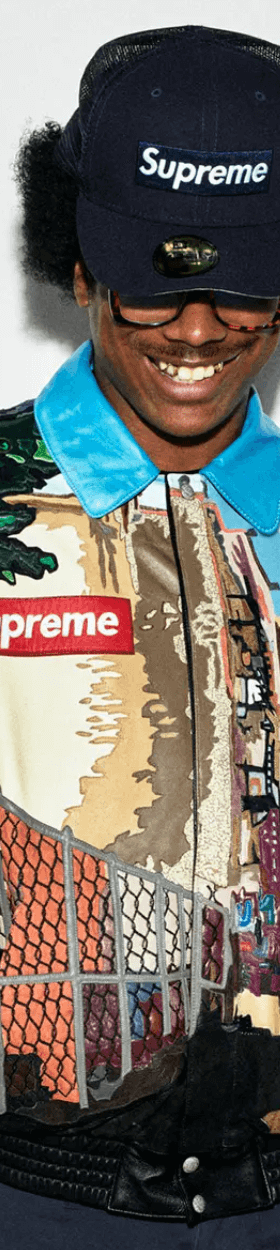 A man wearing a Supreme NYC style colorful graphic coaches jacket with a supreme box logo hat