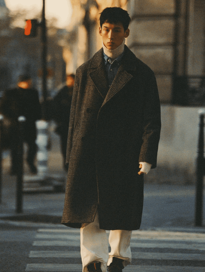 A man walking on the street wearing a Zara outfit featuring a brown jacket and beige turtleneck