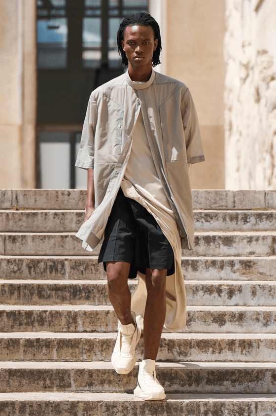 A man walking down steps on a sunny day wearing a Rick Owens outfit featuring a space grey overshirt, black shorts and shoes