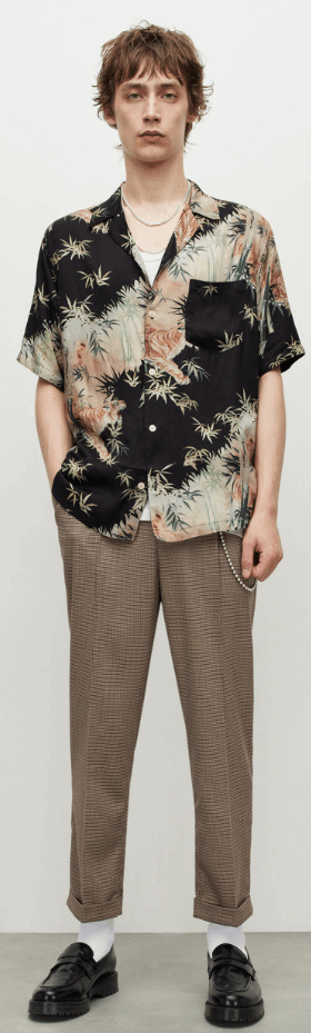 A man standing wearing an AllSaints dark floral short-sleeve button up with beige pants