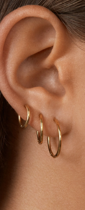 A woman wearing BaubleBar verbena 18k gold earrings