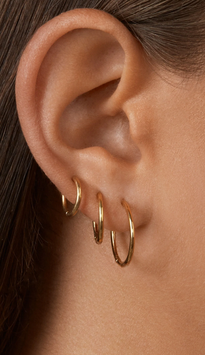 A woman wearing BaubleBar verbena 18k gold earrings