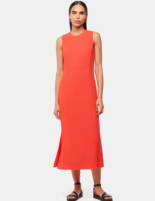 A woman wearing Whistles coral color erin texture midi dress