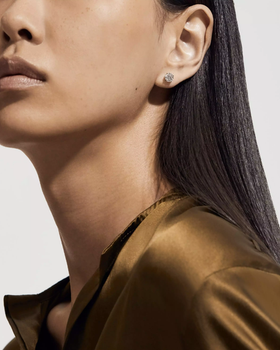 A woman wearing De Beers db classic round brilliant diamond studs
