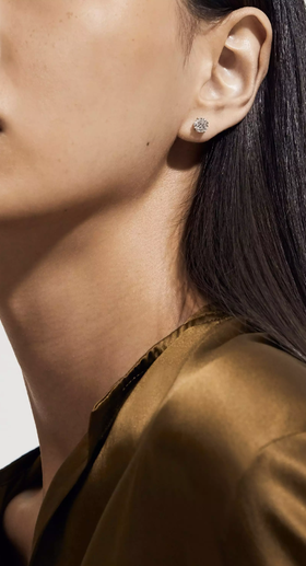 A woman wearing De Beers db classic round brilliant diamond studs