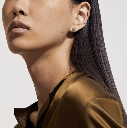 A woman wearing De Beers db classic round brilliant diamond studs