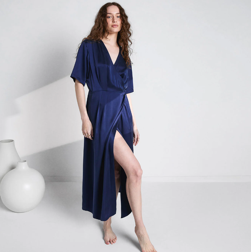 A woman wearing Lunya deep blue washable silk wrap dress