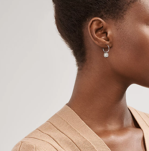 A woman wearing Tiffany & Co. pearl hoop earrings in sterling silver
