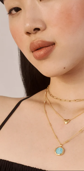A woman wearing Monica Vinader heart chain necklace
