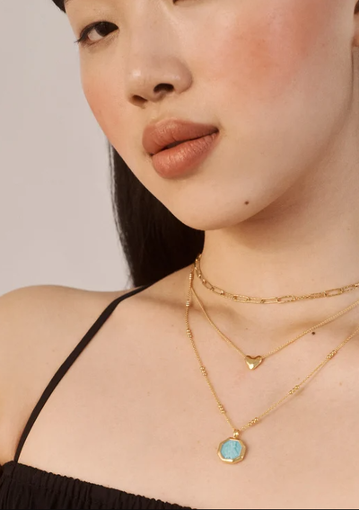A woman wearing Monica Vinader heart chain necklace