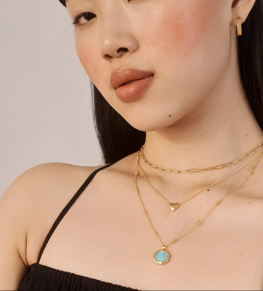 A woman wearing Monica Vinader heart chain necklace