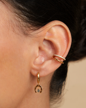 A woman wearing Astrid & Miyu horseshoe charm huggies in gold