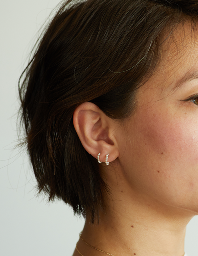 A woman wearing Catbird baby pearl hoop earring (single)