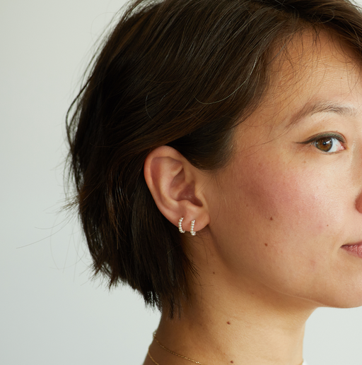 A woman wearing Catbird baby pearl hoop earring (single)