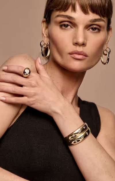A woman wearing Vrai hoops earrings