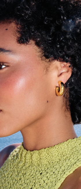 A woman wearing Missoma chubby medium hoop earrings