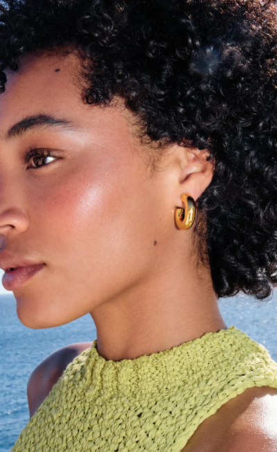 A woman wearing Missoma chubby medium hoop earrings
