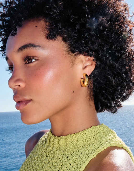 A woman wearing Missoma chubby medium hoop earrings