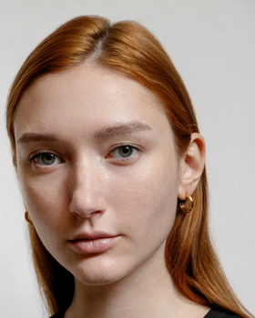 A woman wearing Wolf Circus abbie hoops in gold earrings