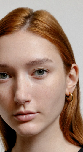 A woman wearing Wolf Circus abbie hoops in gold earrings