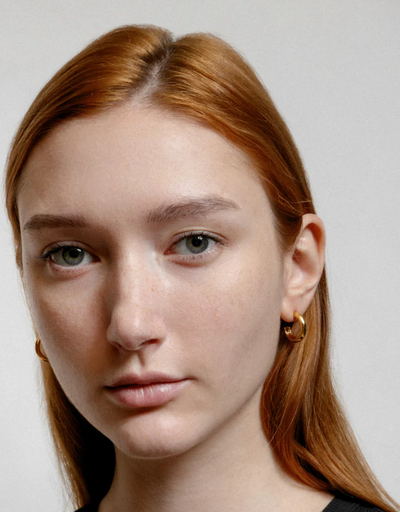 A woman wearing Wolf Circus abbie hoops in gold earrings