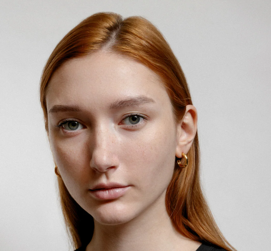 A woman wearing Wolf Circus abbie hoops in gold earrings