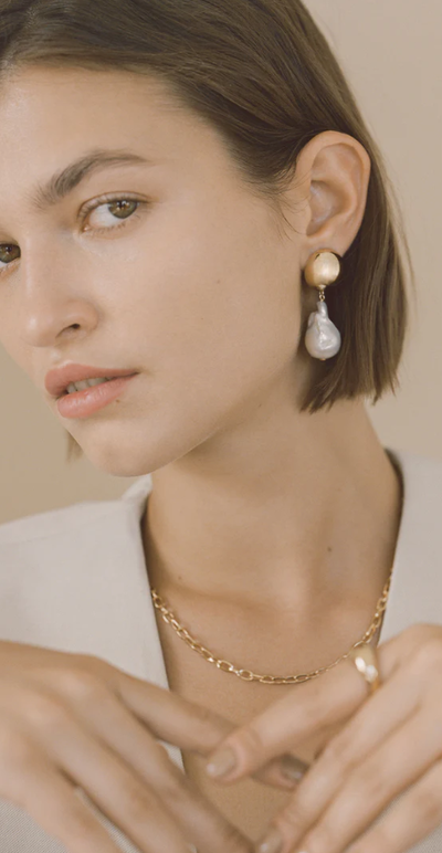 A woman wearing Young Frankk riles baroque pearl earrings
