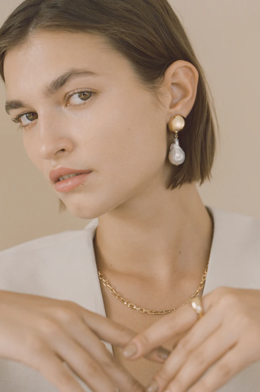 A woman wearing Young Frankk riles baroque pearl earrings