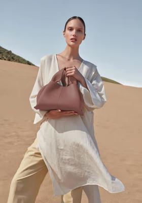 A woman carrying Polene numéro neuf edition blush grainé bag