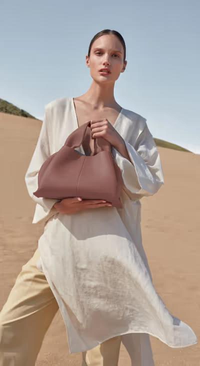 A woman carrying Polene numéro neuf edition blush grainé bag
