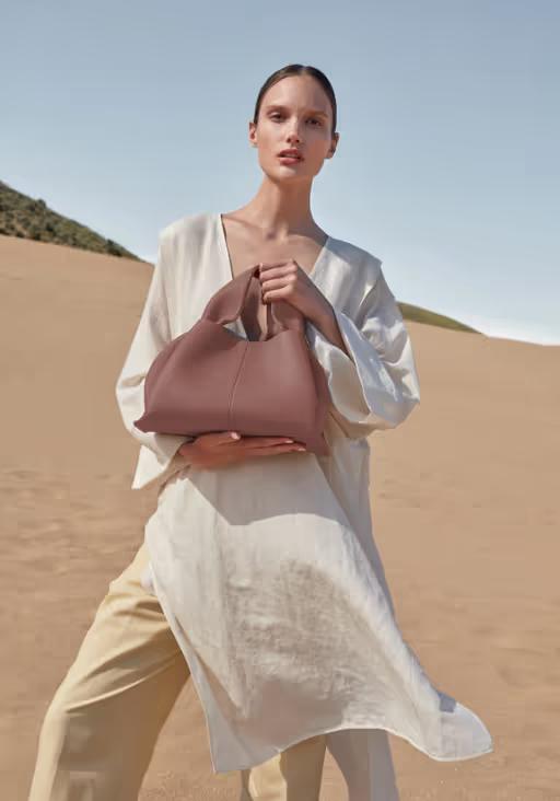 A woman carrying Polene numéro neuf edition blush grainé bag