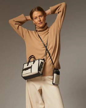 A woman carrying Anya Hindmarch mixed canvas in natural pocket xs cross-body tote bag