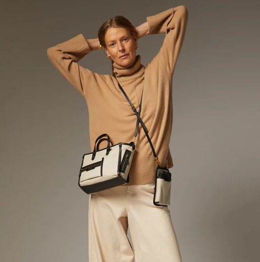 A woman carrying Anya Hindmarch mixed canvas in natural pocket xs cross-body tote bag