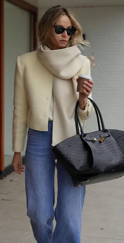 A woman carrying Demellier black small grain bag