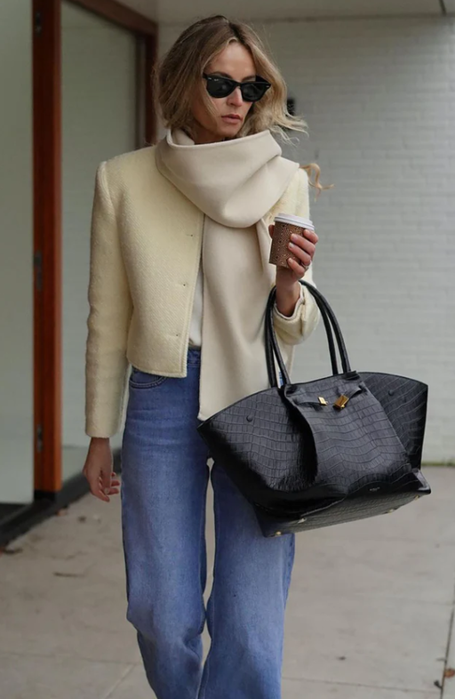 A woman carrying Demellier black small grain bag