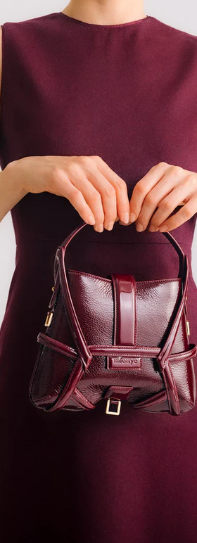 A woman carrying Mlouye s-x2 - patent bordeaux bag