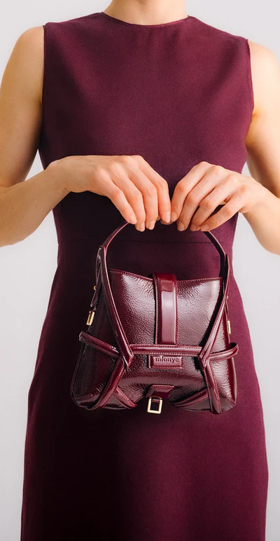 A woman carrying Mlouye s-x2 - patent bordeaux bag
