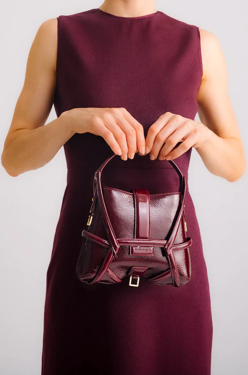 A woman carrying Mlouye s-x2 - patent bordeaux bag