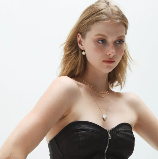 A woman wearing TAI lustrous drop pearl earrings