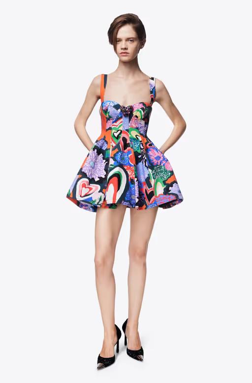 A woman wearing AREA Clothing heart printed denim godet mini dress