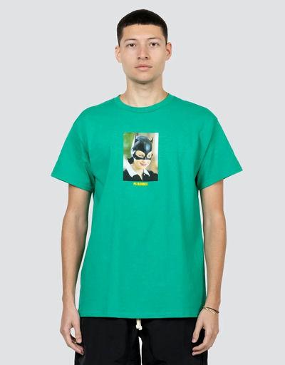 A man wearing a Pleasures green catwoman t-shirt