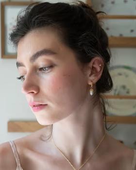 A woman wearing Fable England acorn pearl hoops earrings