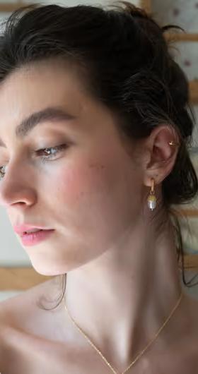 A woman wearing Fable England​ acorn pearl hoops earrings