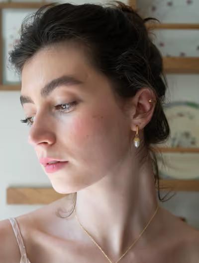A woman wearing Fable England acorn pearl hoops earrings