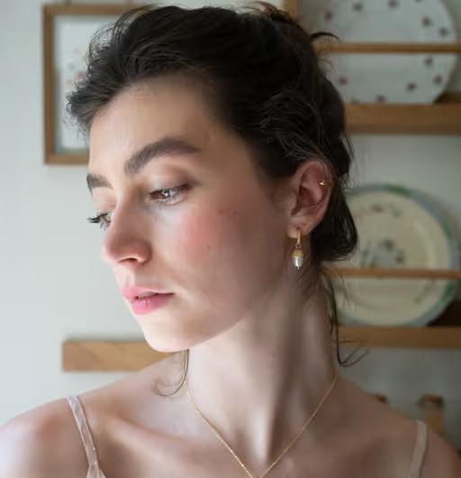 A woman wearing Fable England​ acorn pearl hoops earrings