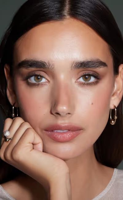 A woman wearing Strathberry crescent hoop earrings - 22 carat gold gilded