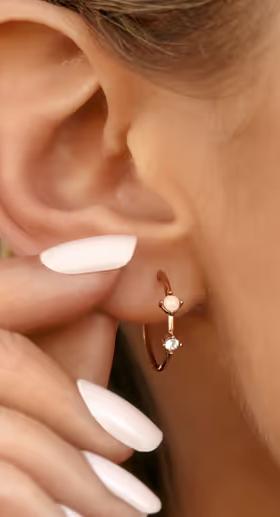 A woman wearing Pura Vida​ opal hoop earrings