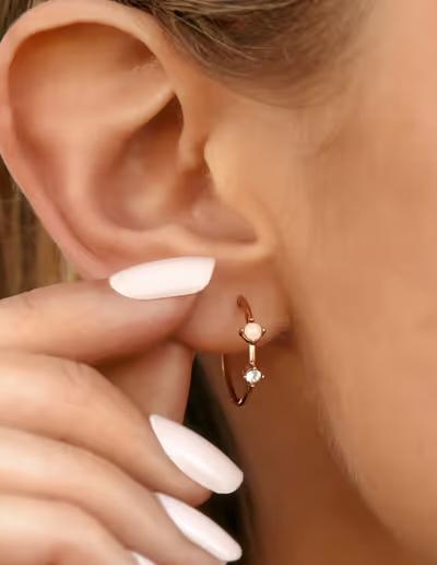 A woman wearing Pura Vida opal hoop earrings