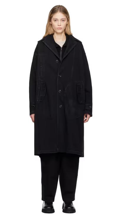 A woman wearing Y's black faded denim coat